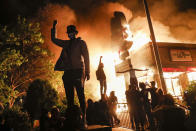 Varios manifestantes protestan a las puertas de un restaurante de comida rápida de Minneápolis que ha sido incendiado en la madrugada del 29 de mayo. (Foto: John Minchillo / AP).