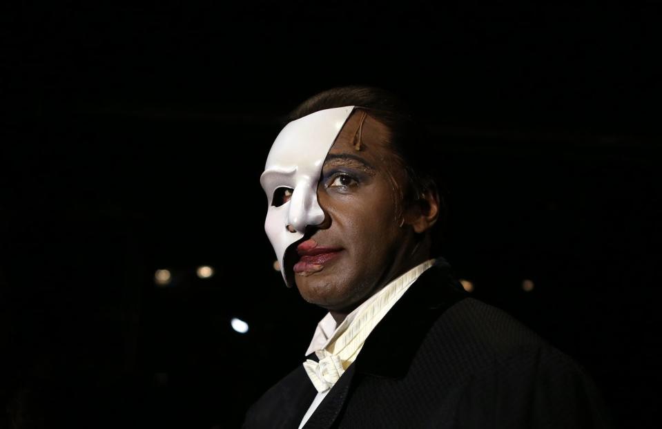 norm lewis wearing a black tuxedo and wearing a white face mask