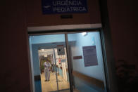 A worker wipes the floor by the pediatric emergency entrance at the Hospital Garcia de Orta in Almada, south of Lisbon, Tuesday, Nov. 30, 2021. A sign posted on the door announces that the hospital is closing its pediatric services after finding out that a health worker who had contact with members of a soccer club affected by an omicron coronavirus variant outbreak was also infected with the same strain. (AP Photo/Armando Franca)