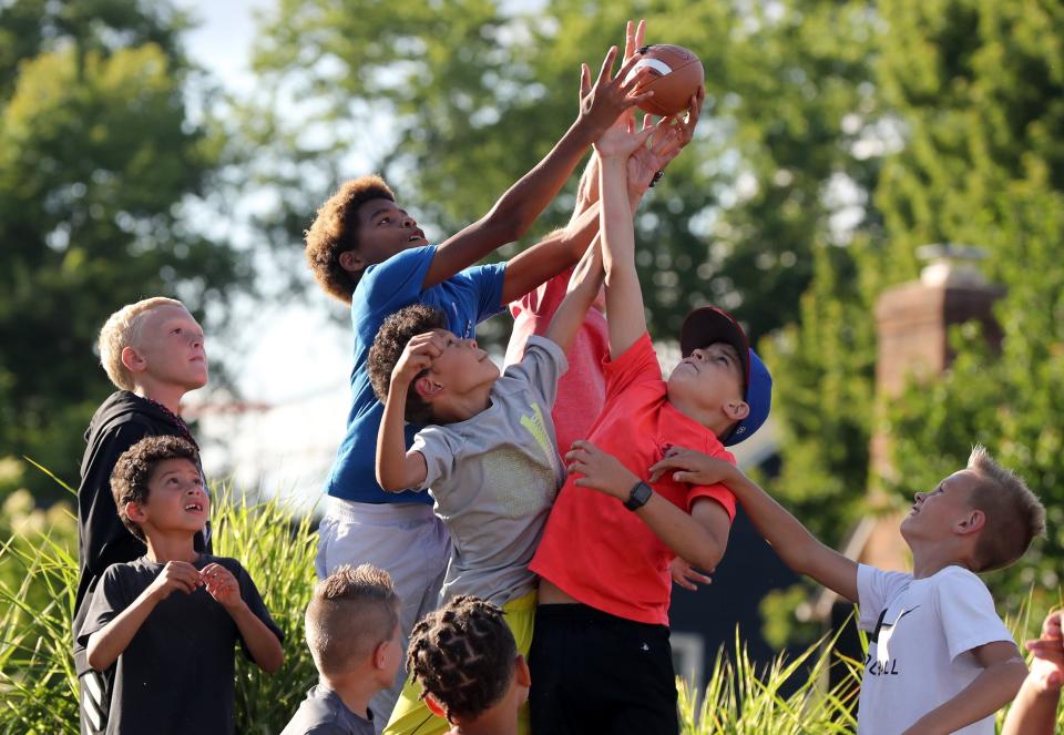 Maurice Alderson, 12, of Grove City,; Donivan Robertson, 9, of Hilliard, and Keaton Griffith, 10, of Hilliard, leap for the football during the Celebration at the Station on June 9.