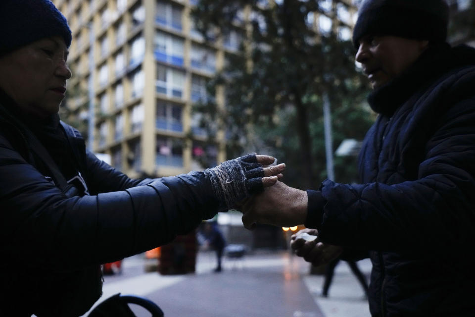 A vendor hands a customer a cup of coffee, in Santiago, Chile, Friday, May 17, 2024. Bitter cold is gripping Chile, a country that doesn't usually experience frost and wind chills this time of year. (AP Photo/Esteban Felix)