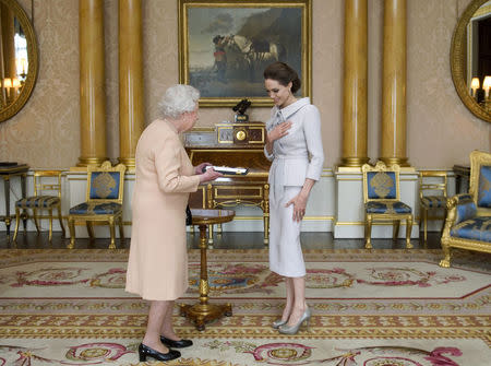 Actress Angelina Jolie is presented with the Insignia of an Honorary Dame Grand Cross of the Most Distinguished Order of St Michael and St George, by Britain's Queen Elizabeth in the 1844 room at Buckingham Palace in London October 10, 2014. REUTERS/Anthony Devlin/pool