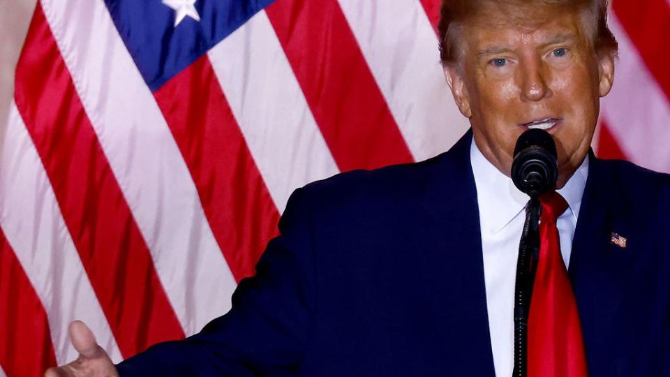 Donald Trump con bandera atrás