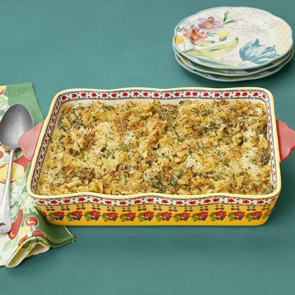 spinach artichoke tuna noodle casserole in floral baking dish on green background