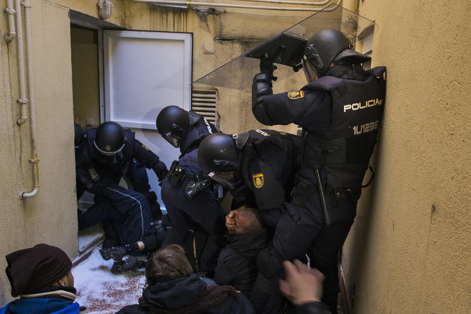 <p>Riot police grab the face of a housing rights activist as he tries to stop Umberto Jimenez’s eviction in Madrid, Feb. 9, 2015. (AP Photo/Andres Kudacki) </p>