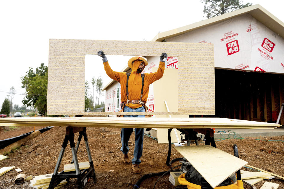 Jose Villanueva carries siding while building a home, Wednesday, Oct. 25, 2023, in Paradise, Calif. The project is partly funded by ReCoverCA, a state program providing money to rebuild homes in disaster areas. (AP Photo/Noah Berger)