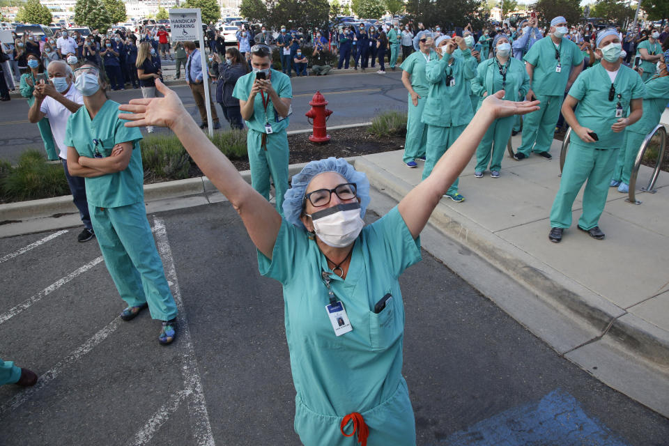 Healthcare worker Diane Alonso celebrates as a giant American flag is unfurled at Intermountain Medical Center Thursday, May 21, 2020, in Murray, Utah, as a way to honor frontline healthcare workers and recognize first responders as they care for COVID-19 patients. (AP Photo/Rick Bowmer)