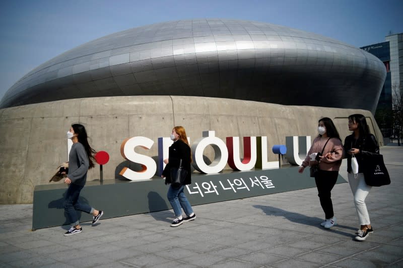 People wearing masks to protect against contracting the coronavirus disease (COVID-19) walk along a street in Seoul, South Korea