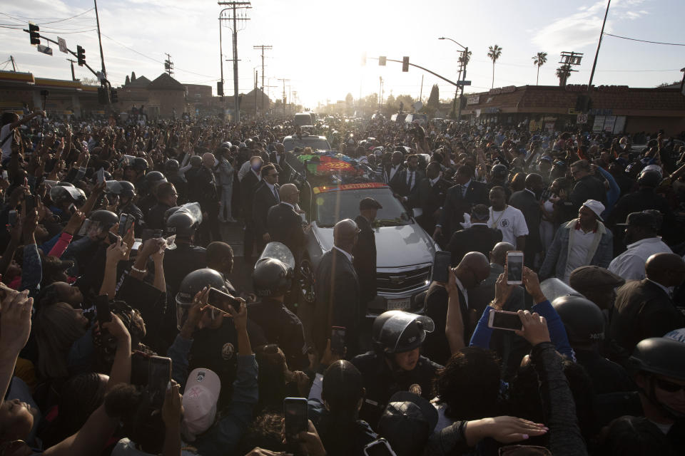A hearse carrying the casket of slain rapper Nipsey Hussle passes through a large crowd on its 25-mile trek through the streets of the city Thursday, April 11, 2019, in Los Angeles. Hussle was shot and killed March 31 outside his The Marathon clothing store in South Los Angeles. (AP Photo/Jae C. Hong)