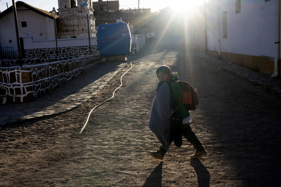 A student walks past a community water tank in Huancar, Jujuy Province, Argentina, Tuesday, April 25, 2023. Argentina's right-wing “anarcho-capitalist” President Javier Milei has announced a broad deregulation sweep, slashing costs for mining companies in an effort to lure investors amid deepening economic crisis. (AP Photo/Rodrigo Abd)