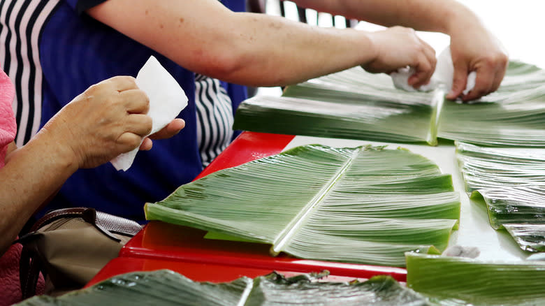People setting a table with banana leaves