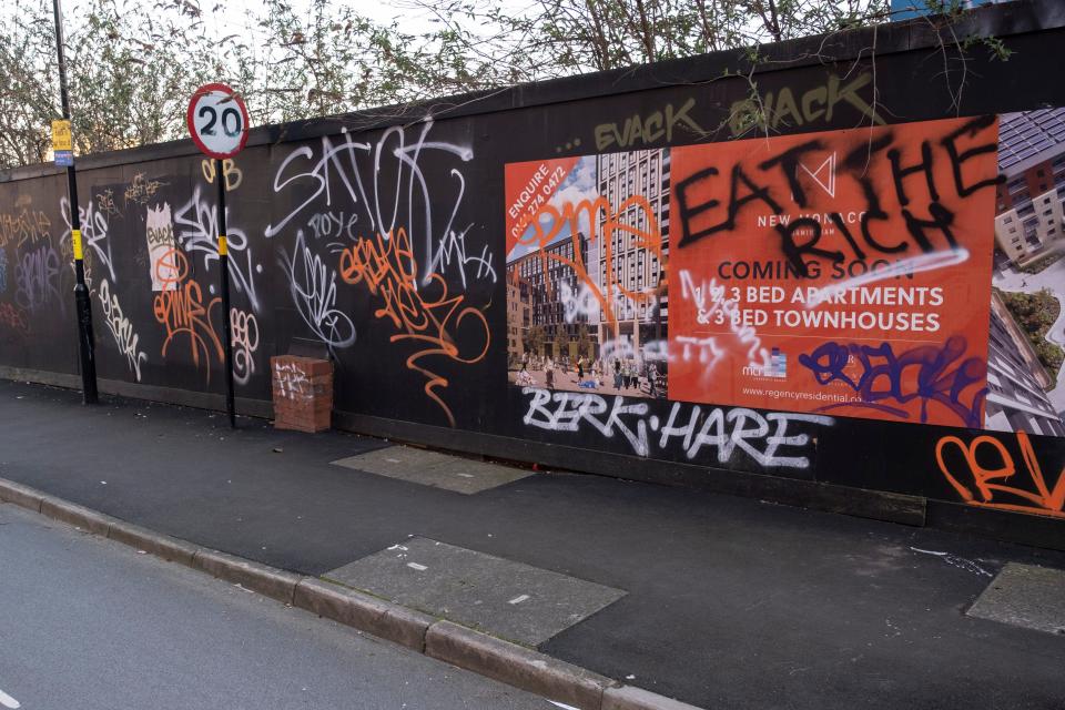 A wall covered in graffiti, including the words "eat the rich."