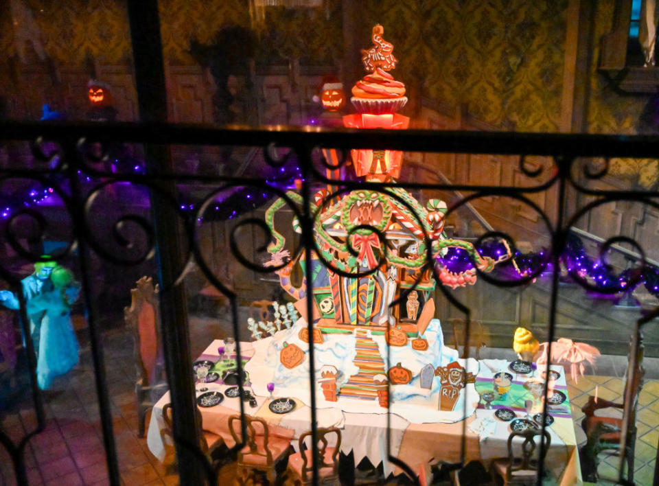 A tall gingerbread mansion with wreath, pumpkin, and ribbon decor, sits 10 feet high inside Haunted Mansion Holiday