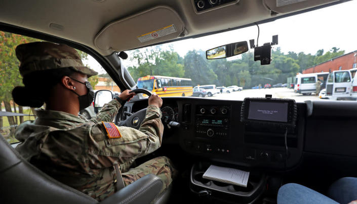 A National Guard member drives a school bus around the base with a safety trainer in Reading, Massachusetts, on Sept. 15, 2021. The state deployed 200 members to help get students to school. (David L. Ryan / Getty Images)