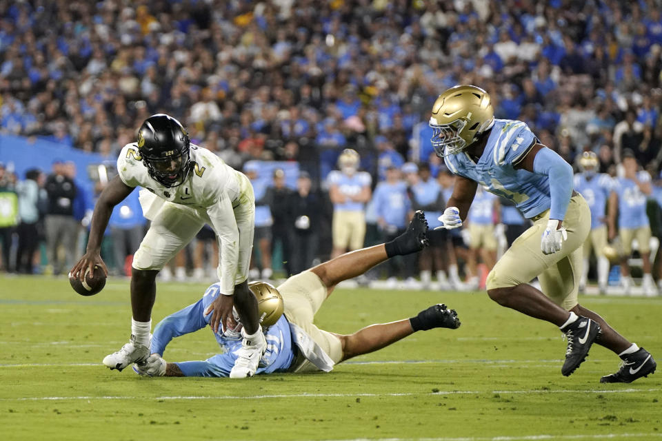 Colorado quarterback Shedeur Sanders, left, is tripped up by UCLA defensive lineman Laiatu Latu, center, before lineman Gabriel Murphy, right, tackles him and forces a fumble during the second half of an NCAA college football game Saturday, Oct. 28, 2023, in Pasadena, Calif. Sanders recovered the ball. (AP Photo/Mark J. Terrill)