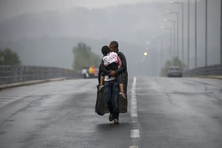 Syrian refugee kisses his daughter as he walks through a rainstorm towards Greece's border with Macedonia, near the Greek village of Idomeni, September 10, 2015. REUTERS/Yannis Behrakis