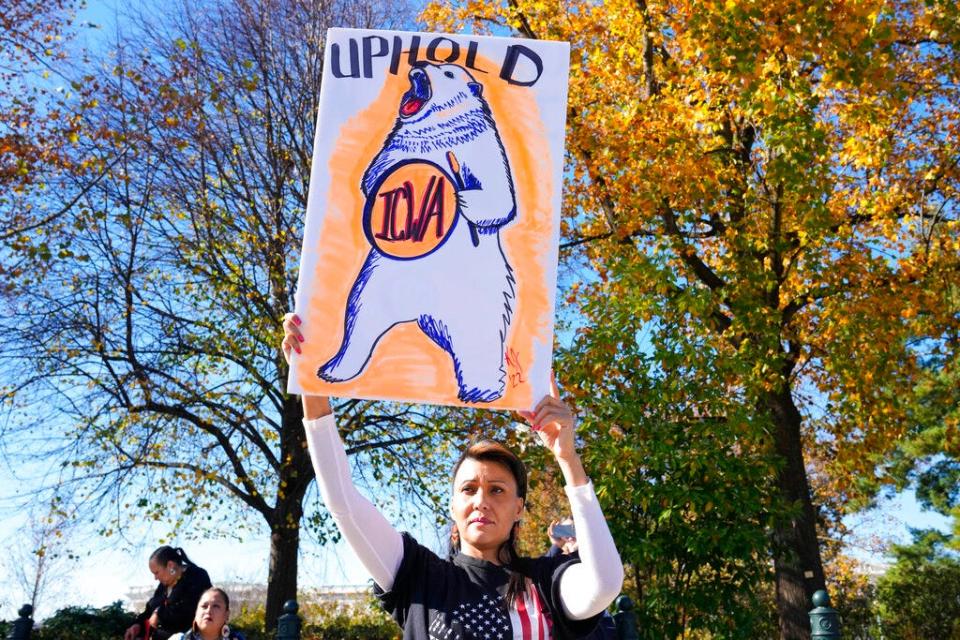 A demonstrator stands in front of the U.S. Supreme Court as the court hears arguments over the Indian Child Welfare Act on Nov. 9, 2022, in Washington. The Supreme Court is wrestling with a challenge to a federal law that gives preference to Native American families in foster care and adoption proceedings of Native children.