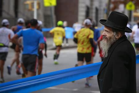 A Hasidic Jewish man watches as runners make their way through the Williamsburg section of the borough of Brooklyn during the New York CIty Marathon in New York, November 3, 2013. REUTERS/Shannon Stapleton