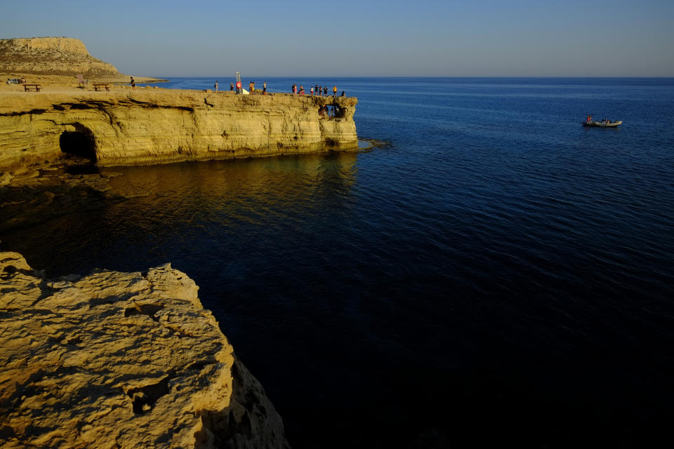 Tourists visit the sea caves during sunset at the southern coastal resort of Ayia Napa in southeast Mediterranean island of Cyprus, Sunday, May 29, 2022. Hundreds of Russian and Ukrainian Orthodox faithful visiting Cyprus would stream daily past the icon of the Virgin Mary at Kykkos Monastery to venerate the relic that tradition dictates was fashioned by Luke the Evangelist and blessed by the Virgin herself. But a European Union ban on flights to and from Russia as a result of Russia's invasion of Ukraine has meant a loss of 800,000 vacationers - a fifth of all tourists to Cyprus in record-setting 2019. (AP Photo/Petros Karadjias)