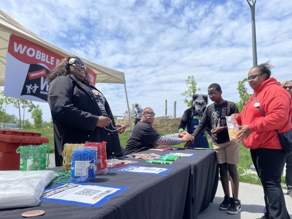 Longtime IMMAWII volunteer Tanisha Butts distributes wrist bands, buttons and beads at the registration table before the Wobble world record attempt Saturday.