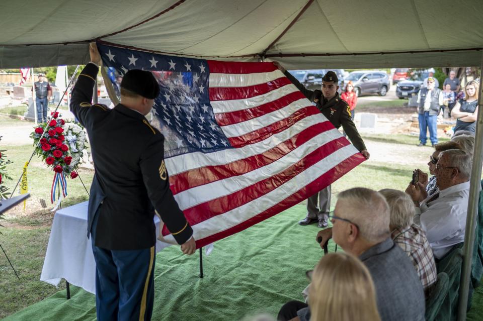 Soldiers fold an American flag during Tech. Sgt. Turner Yearwood Johnston's burial service. He was laid to rest near his parents.