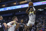 Utah Jazz guard Kris Dunn (11) drives to the basket over Sacramento Kings guard De'Aaron Fox (5) and guard Davion Mitchell during the first half of an NBA basketball game in Sacramento, Calif., Sunday, March 31, 2024. (AP Photo/Randall Benton)