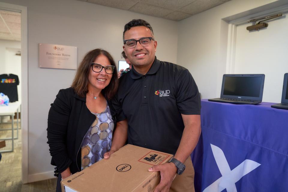 Michelle Gilbert, vice president of public relations for Comcast Cable Heartland Region, and LAUP Executive Director Johnny Rodriguez present laptops to students.