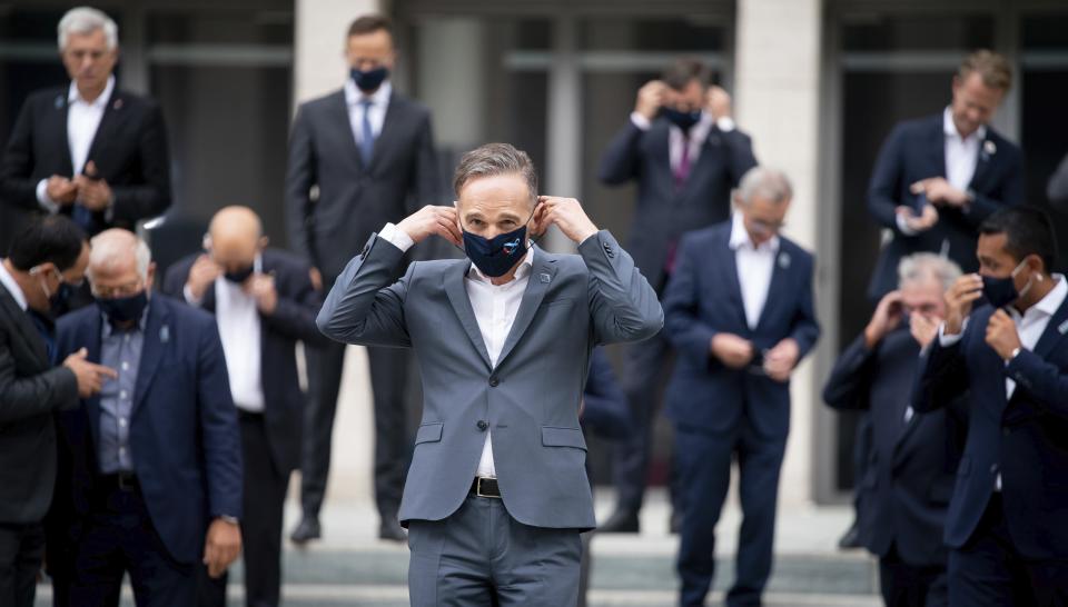 Foreign Minister Heiko Maas, wearing a mouth-and-nose protector, meets his EU counterparts for the family photo on the fringes of the informal talks between the EU Foreign Ministers and their EU counterparts. The topics of the so-called Gymnich meeting include developments in Belarus and the dispute over natural gas in the eastern Mediterranean between Turkey and the EU states of Greece and Cyprus. (Kay Nietfeld/dpa via AP)