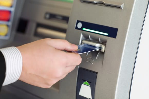 Hand inserting a card into an ATM