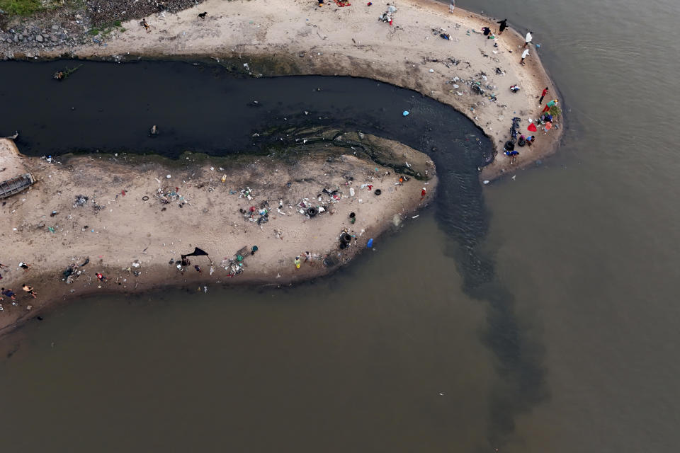 Varias personas pescan junto a un desagüe en el río Paraguay, en Asunción, Paraguay, el 28 de enero de 2024. (AP Foto/Jorge Saenz)