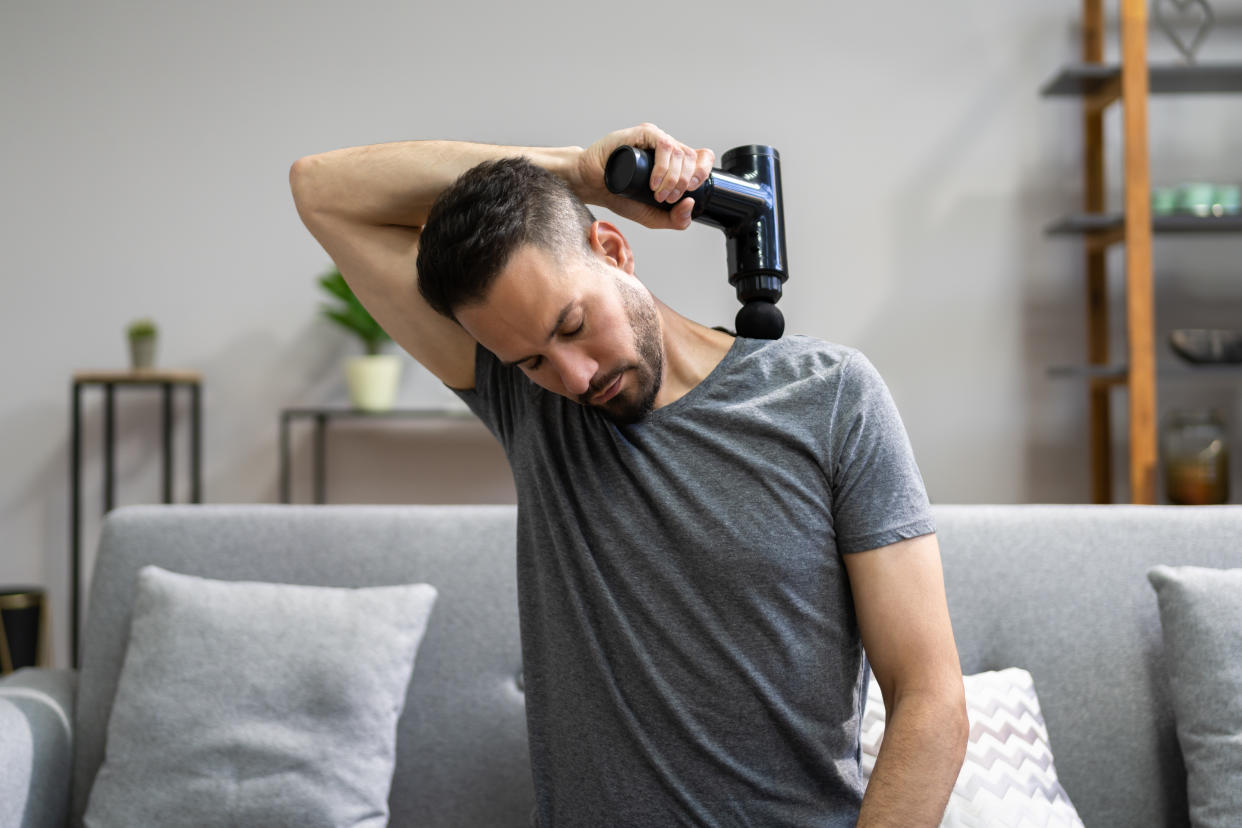 someone using a Massage Gun Machine on their shoulder