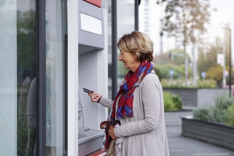 Senior woman using ATM in the city.