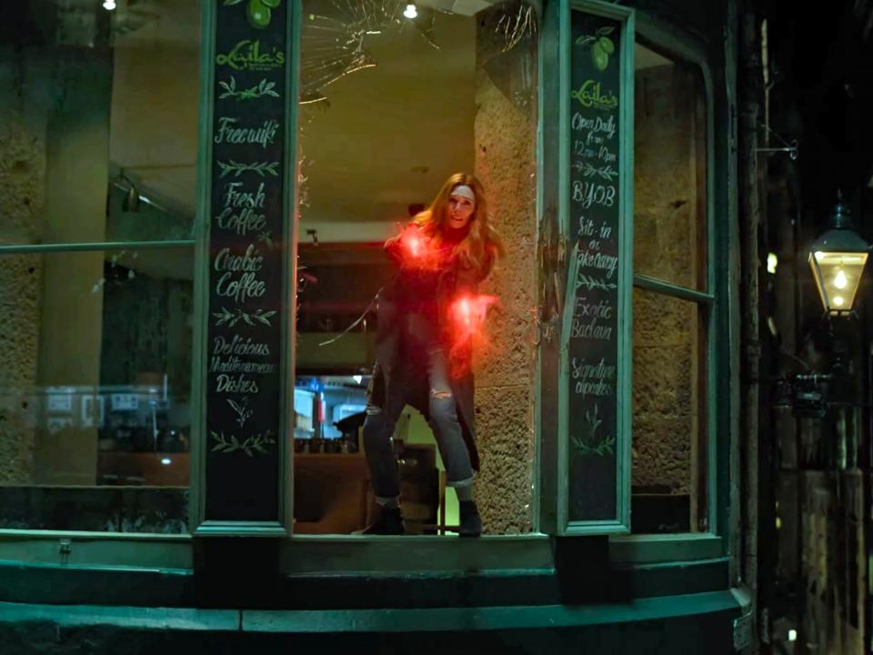 wanda standing in the window of a cafe with her hands glowing red in avengers infinity wars
