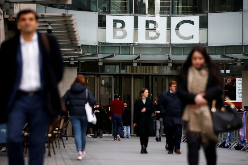 FILE PHOTO: Pedestrians walk past a BBC logo at Broadcasting House, as the corporation announced it will cut around 450 jobs from its news division, in London