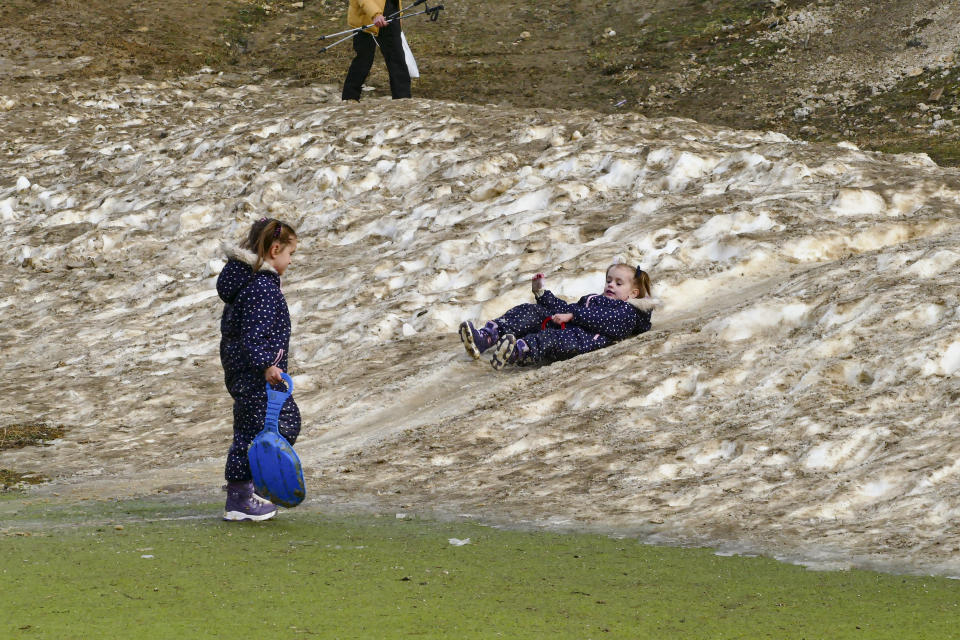 Children play on a patch of melting artificial snow in Vlasic, a ski resort affected by unusual warm weather in Bosnia, Tuesday, Jan. 3, 2023. The exceptional wintertime warmth is affecting ski resorts across Bosnia, prompting tourism authorities in parts of the country to consider declaring a state of natural emergency. (AP Photo/Almir Alic)