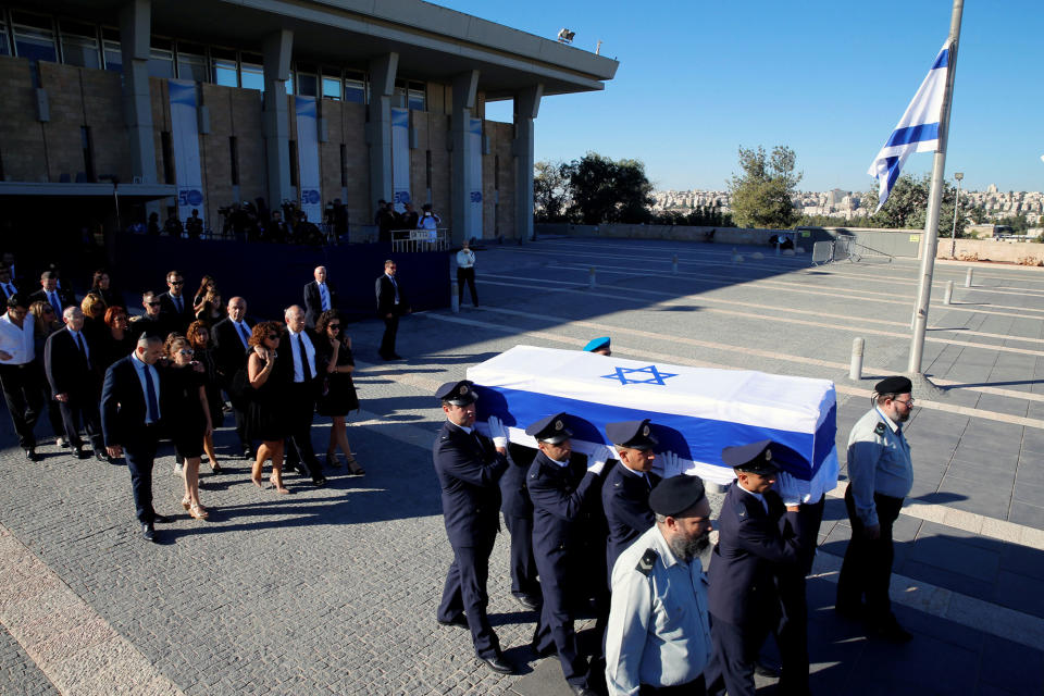 <p>Family members of former Israeli President Shimon Peres walk behind his flag-draped coffin carried during a ceremony at the Knesset, the Israeli parliament, before it is transported to Mount Herzl Cemetery ahead of the funeral in Jerusalem on Sept. 30, 2016. (REUTERS/Ammar Awad) </p>
