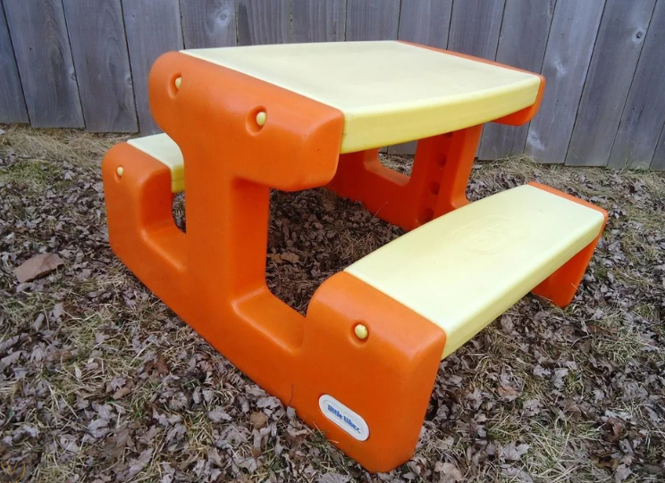 A small, plastic children's picnic table with attached benches
