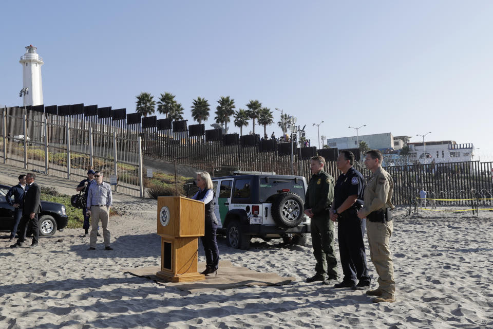 Secretary of Homeland Security Kirstjen Nielsen, center at podium, speaks in front of the border wall separating Tijuana, Mexico, behind, and San Diego, Tuesday, Nov. 20, 2018, in San Diego. Nielsen said Tuesday an appeal will be filed on the decision by a judge to bar the Trump administration from refusing asylum to migrants who cross the southern border illegally. (AP Photo/Gregory Bull)