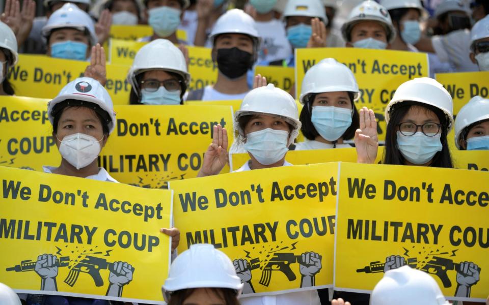 Demonstrators hold placards as they rally against the military coup in Yangon - REUTERS