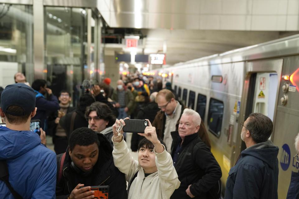 Riders take photos and videos as they exit the first Long Island Railroad train to arrive in Grand Central Station in New York, Wednesday, Jan. 25, 2023. After years of delays and massive cost overruns, one of the world's most expensive railway projects on Wednesday began shuttling its first passengers between Long Island to a new annex to New York City's iconic Grand Central Terminal. (AP Photo/Seth Wenig)