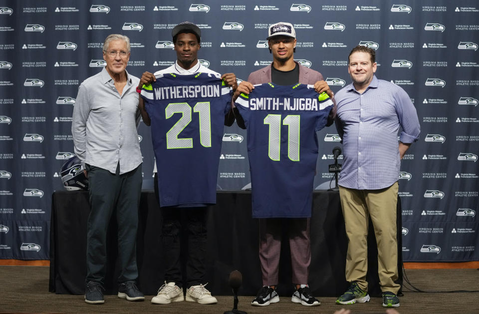 Seattle Seahawks head coach Pete Carroll, from left, poses with first-round NFL football draft picks Devon Witherspoon, a cornerback from Illinois, and Jaxon Smith-Njigba, a wide receiver from Ohio State, along with general manager John Schneider, Friday, April 28, 2023, during a press conference at the team's headquarters in Renton, Wash. (AP Photo/Lindsey Wasson)
