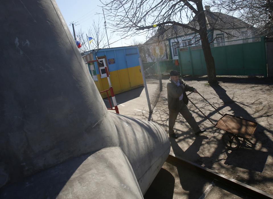 In this photo taken Monday, March 24, 2014, a man walks past a concrete block placed to limit traffic at the border crossing between Ukraine and Russia in the village of Vyselki, eastern Ukraine. Ever since the 1991 breakup of the Soviet Union, the village of Vyselki has been split between Ukraine and Russia. For years its residents have continued to live together peacefully, doing most of their shopping in one country and paying their electricity bills in another. But after Russia seized the Crimean Peninsula from Ukraine, the Ukrainian villagers fear a further incursion of Russian troops, while the Russians say they would welcome their protection against the new pro-Western government in Kiev. (AP Photo/Sergei Grits)