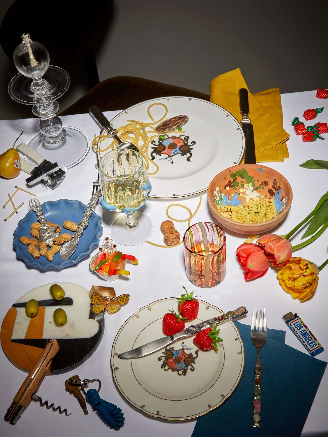 a table is filled with dishes of varying colors and sizes with some silverware and glassware and a small glass candelabra