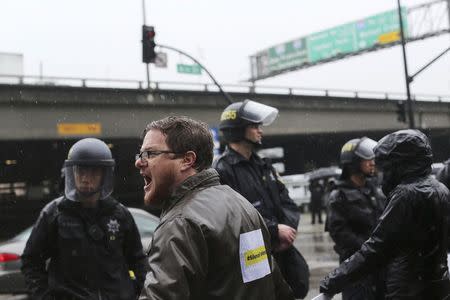 A demonstrator shouts at police while blocking the doors to the Oakland police headquarters during protest against killings of unarmed black men by police officers in Oakland, California December 15, 2014. REUTERS/Robert Galbraith