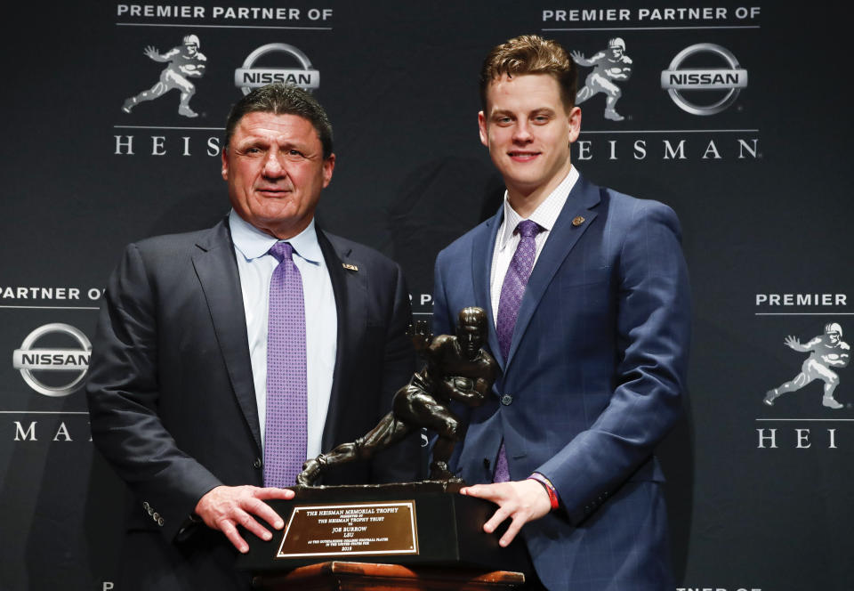 NCAA college football player, LSU quarterback Joe Burrow, right, and head coach Ed Orgeron pose for a photo after Burrow wins the Heisman Trophy, Saturday, Dec. 14, 2019, in New York. (AP Photo/Jason Szenes)