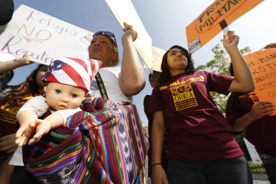 FILE - In this July 3, 2014, file photo, immigration activists Amarily Ortiz, left, and Mayra Sixtos, demand the Mexican government to take more measures to protect and respect the rights of unaccompanied minors and families crossing Mexico's territory during a protest outside the Mexican Consulate in Los Angeles. The U.S. federal government may house unaccompanied migrant children on a California Army National Guard base in central California, officials said. The Pentagon on Friday, April 2, 2021, approved the use of Camp Roberts to temporarily house children traveling alone, according to a defense official. (AP Photo/Damian Dovarganes, File)