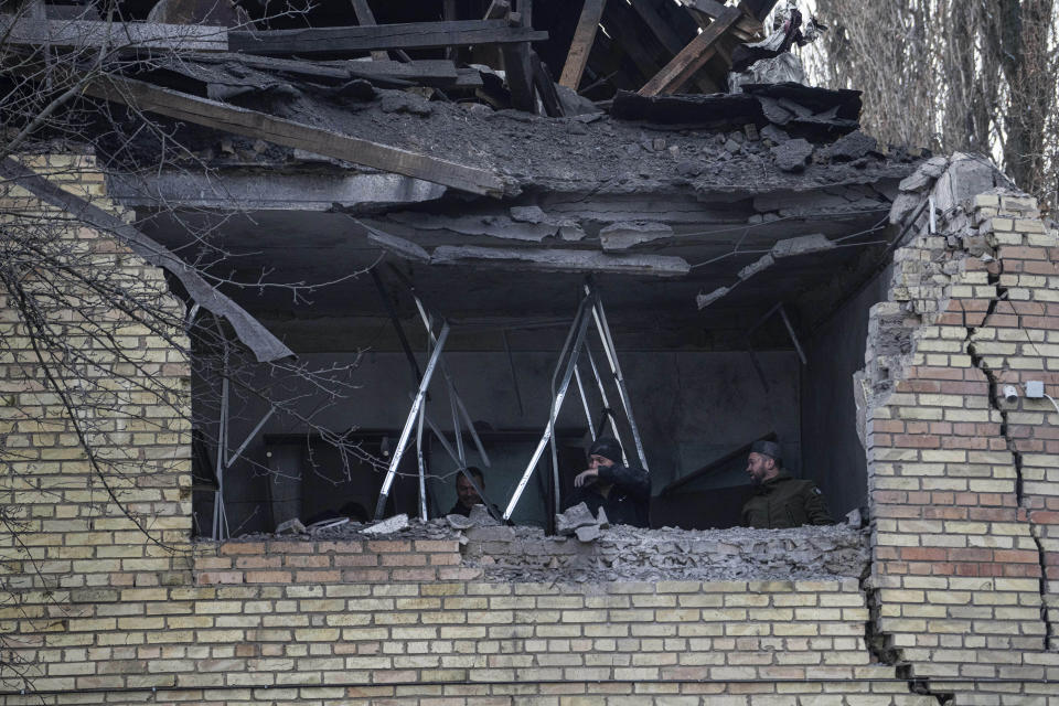 People check a tax office building, that was heavily damaged in Russian shelling, in Kyiv, Ukraine, Wednesday, Dec. 14, 2022. (AP Photo/Evgeniy Maloletka)