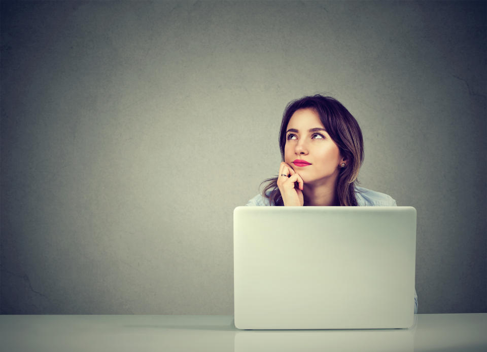 young business woman thinking daydreaming sitting at desk with laptop computer