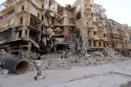 A man walks with the aid of a crutch past damaged buildings in the old city of Aleppo June 27, 2015. REUTERS/Abdalrhman Ismail