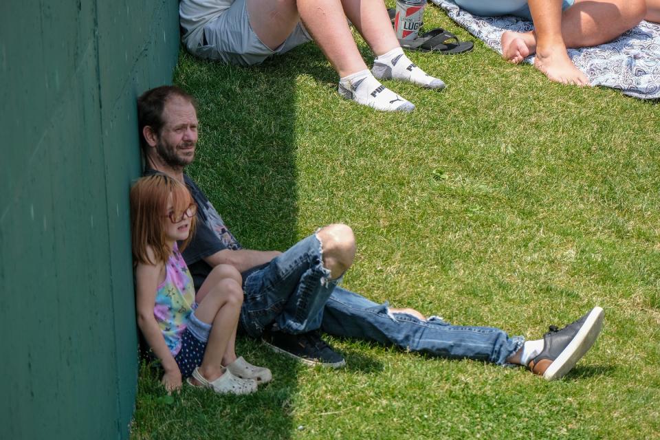 Barri McDaniel from Lansing and his daughter Betty Jo, 6, find some shade up against the wall in the outfield at Jackson Field on Father's Day Sunday, June 18, 2023.